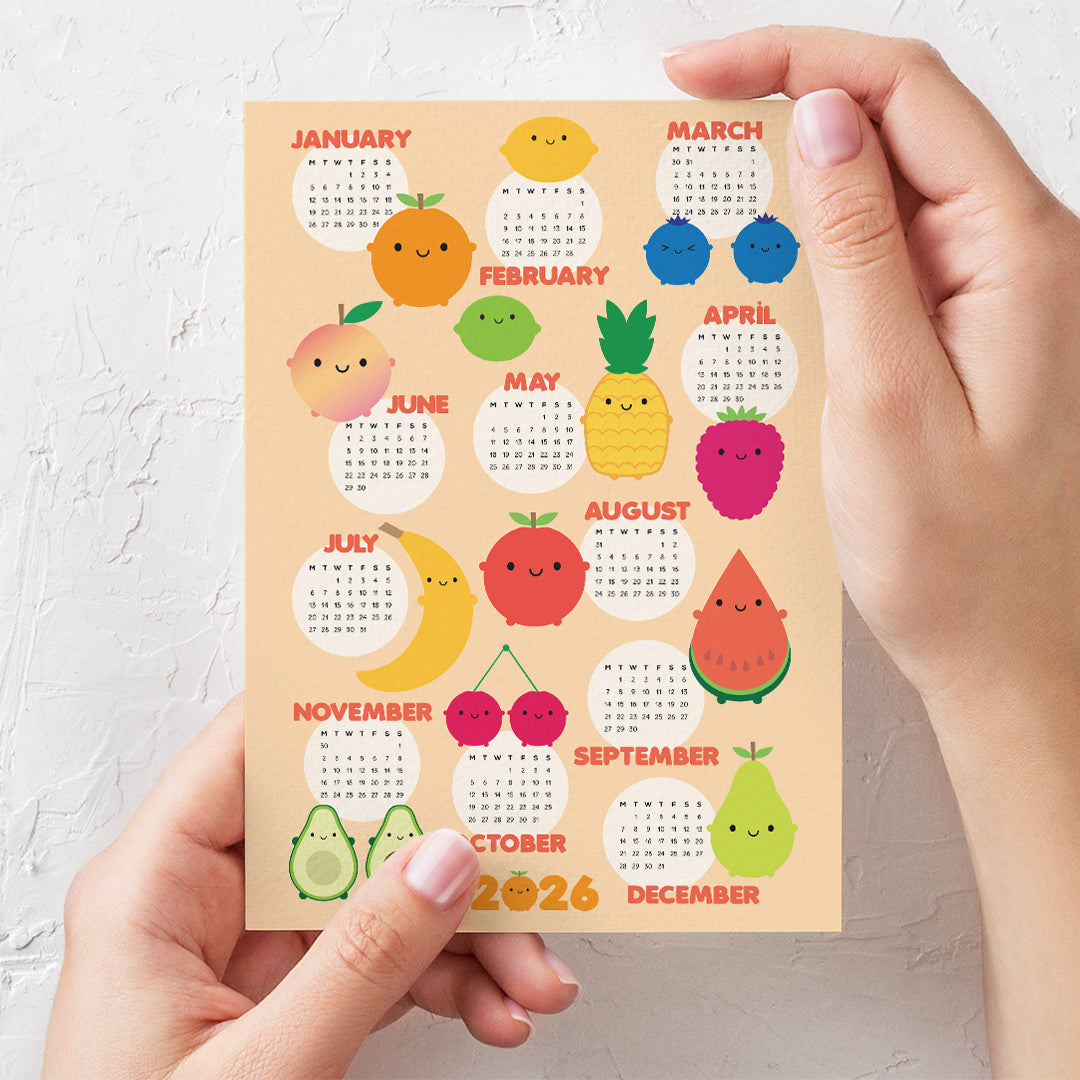 Postcard calendar with fruit-themed design held in hands to show scale (A6)