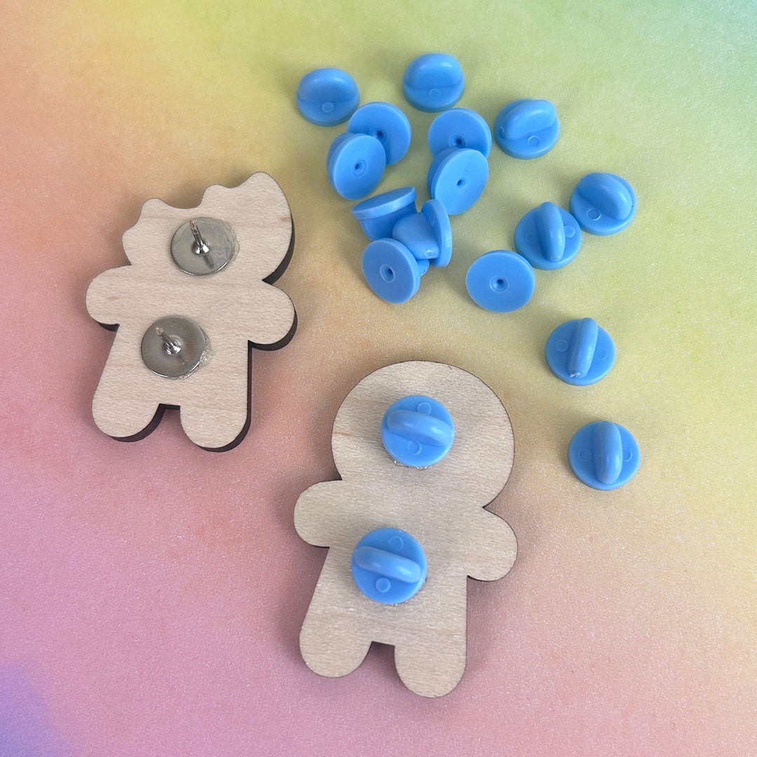 A pile of rubber clutch backs next to wooden brooches