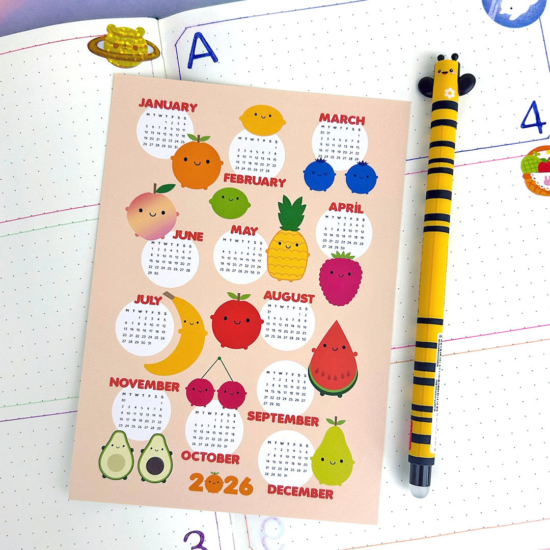 Calendar with fruit-themed design for 2026 on a journal with a pen.