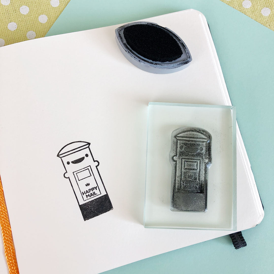 The inked up Postbox stamp on a block and the stamped design on a notebook page