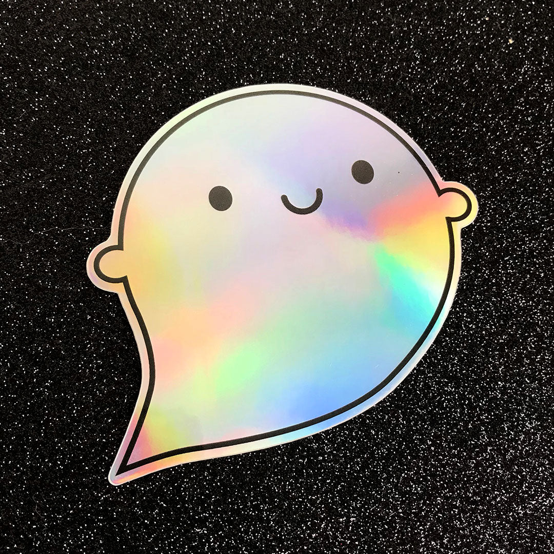 A die cut vinyl sticker of a happy ghost showing the colourful rainbow holographic foil