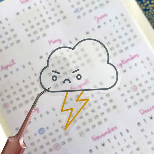 A clear transparent Thunder Cloud sticker held over a printed page
