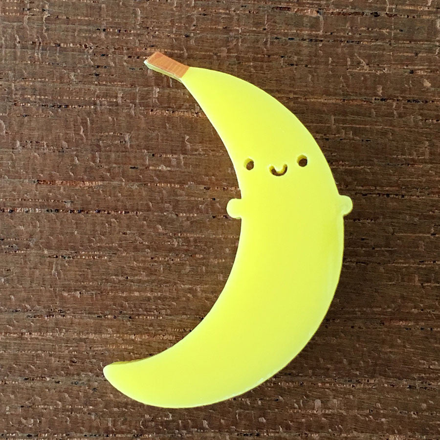 A happy kawaii Banana brooch laser cut from yellow acrylic with a hand drawn brown stalk