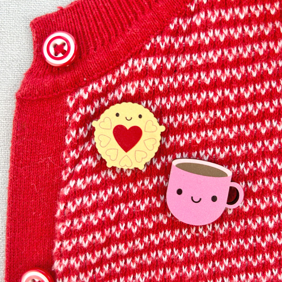 Jammie Dodger & Pink Cup pinned to a red cardigan