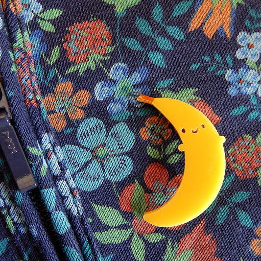A happy banana acrylic brooch pinned to floral hoodie