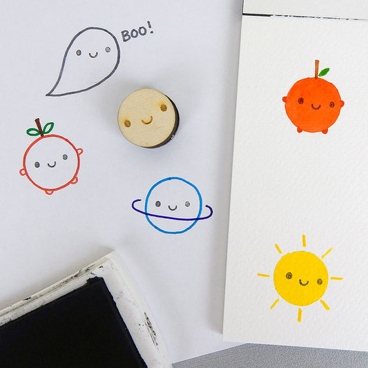 The Smiley Face stamp with examples of stamping the face on paintings and doodles