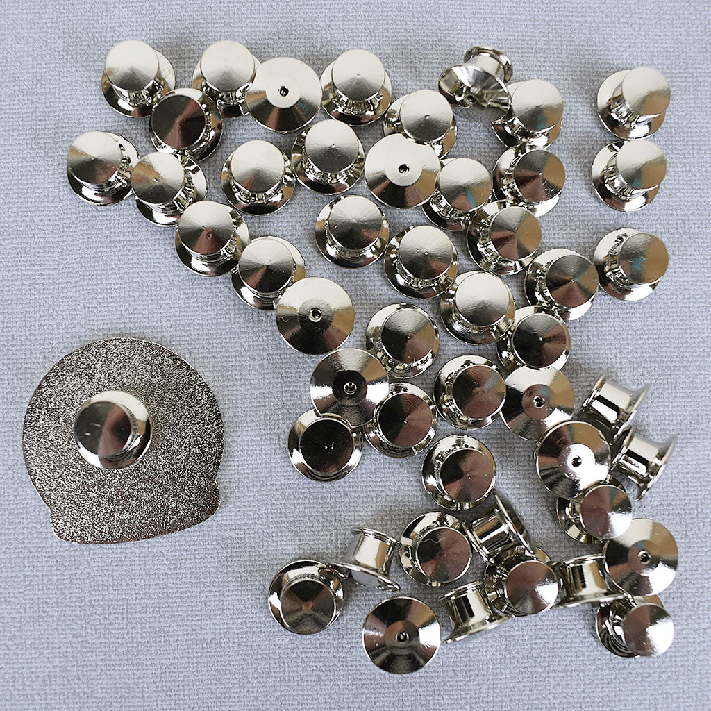 A pile of locking backs next to an enamel pin