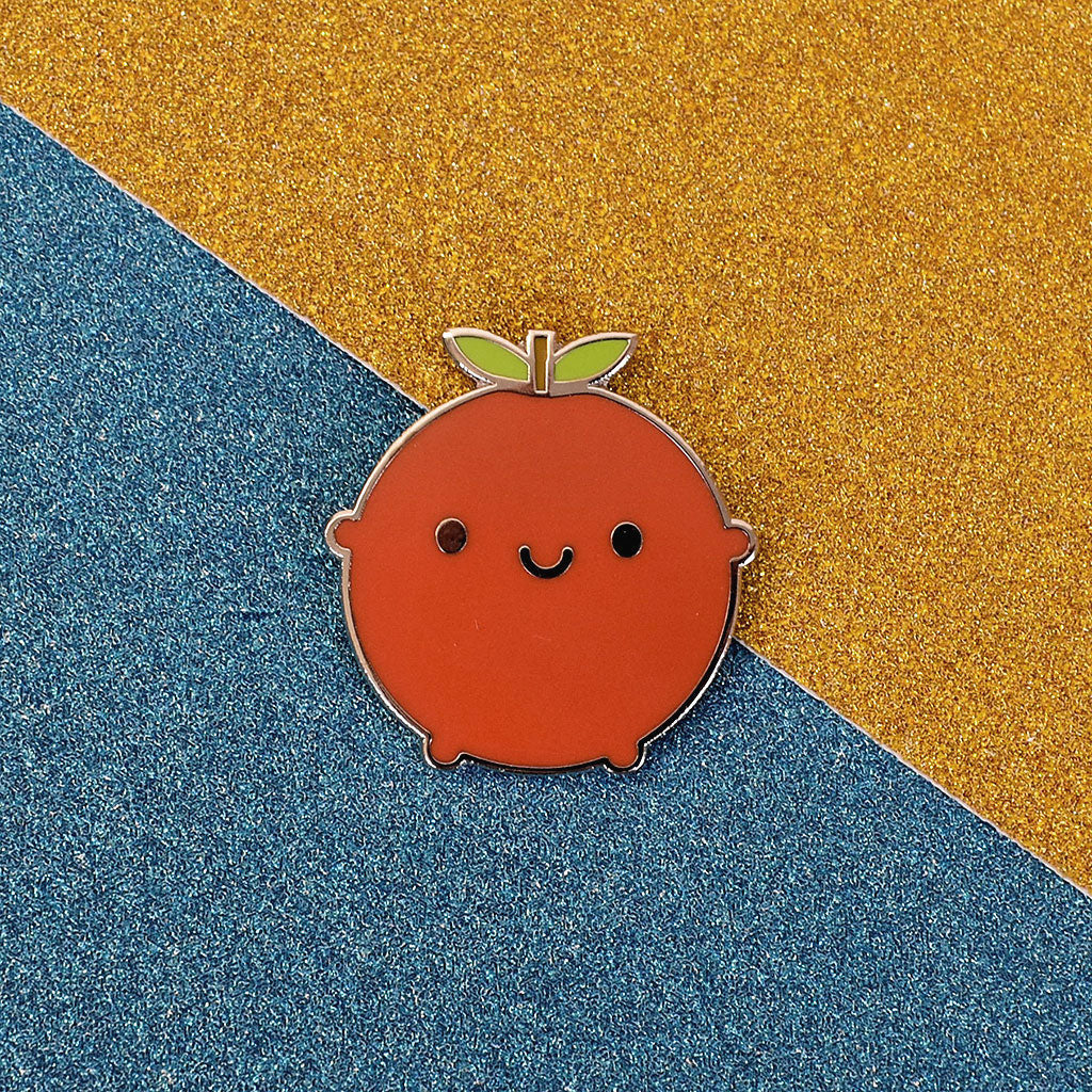 A happy red apple enamel pin on a glittery background