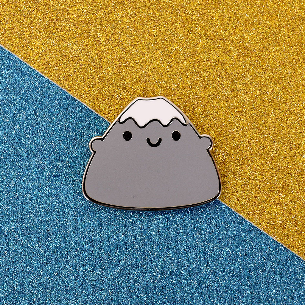 A Mt Fuji enamel pin on a glittery background