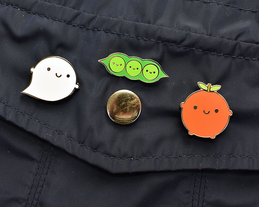 Apple, Ghost and Peapod enamel pins, pinned to a coat pocket
