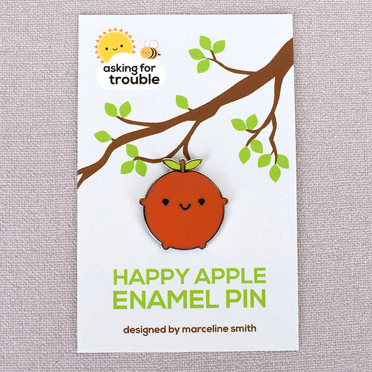 Each enamel pin comes packaged on an illustrated backing card made to look like the apple is hanging from a tree branch