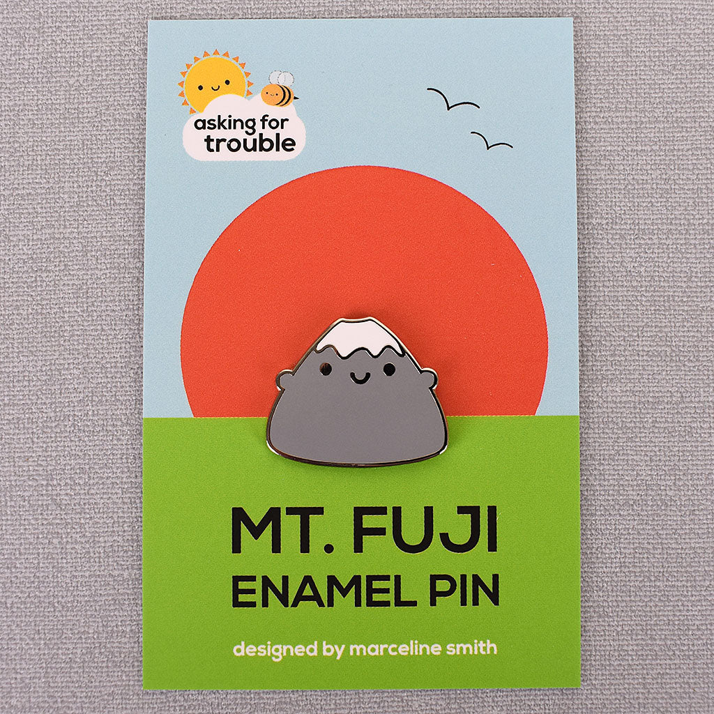 Each enamel pin comes packaged on an illustrated backing card showing a simple landscape