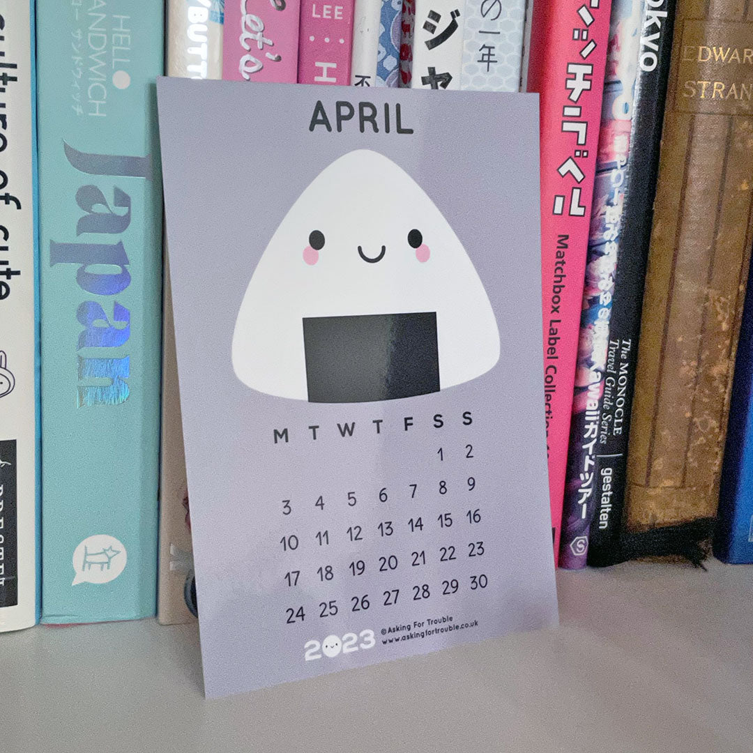 The April postcard with Onigiri on a shelf with Japan books