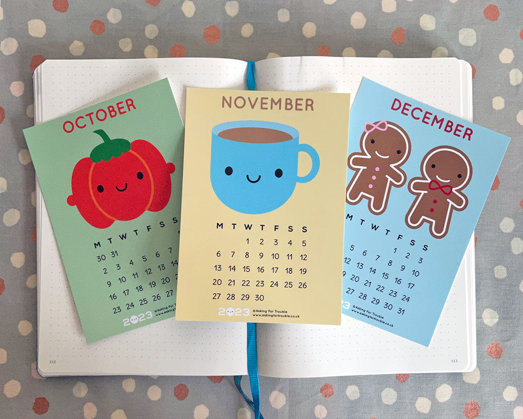 The October, November & December postcards on an open notebook