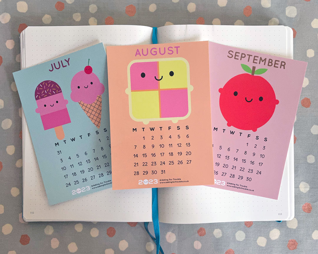 The July, August and September postcards on an open notebook