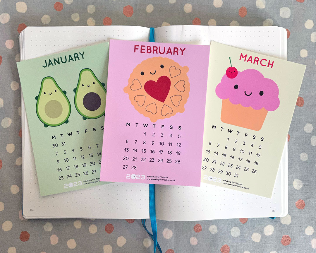 The January, February and March postcards on an open notebook
