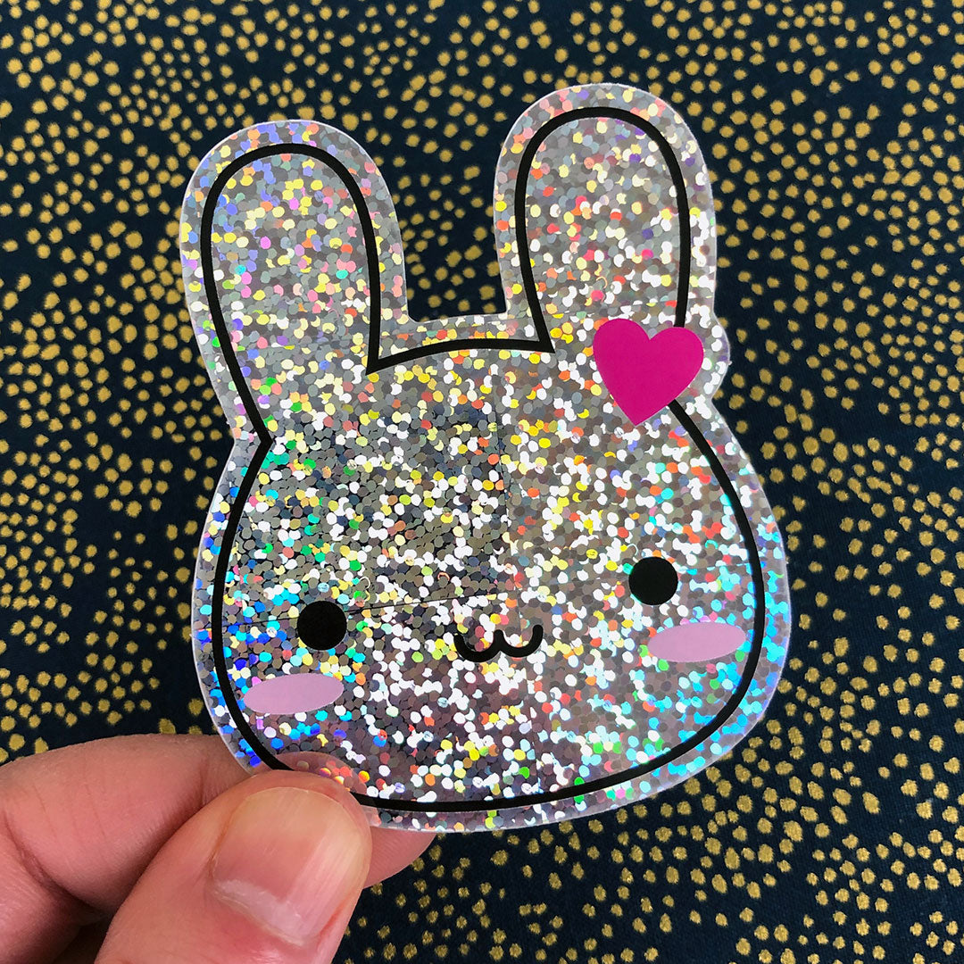 A die cut vinyl sticker of a happy bunny rabbit showing the sparkly holographic glitter foil