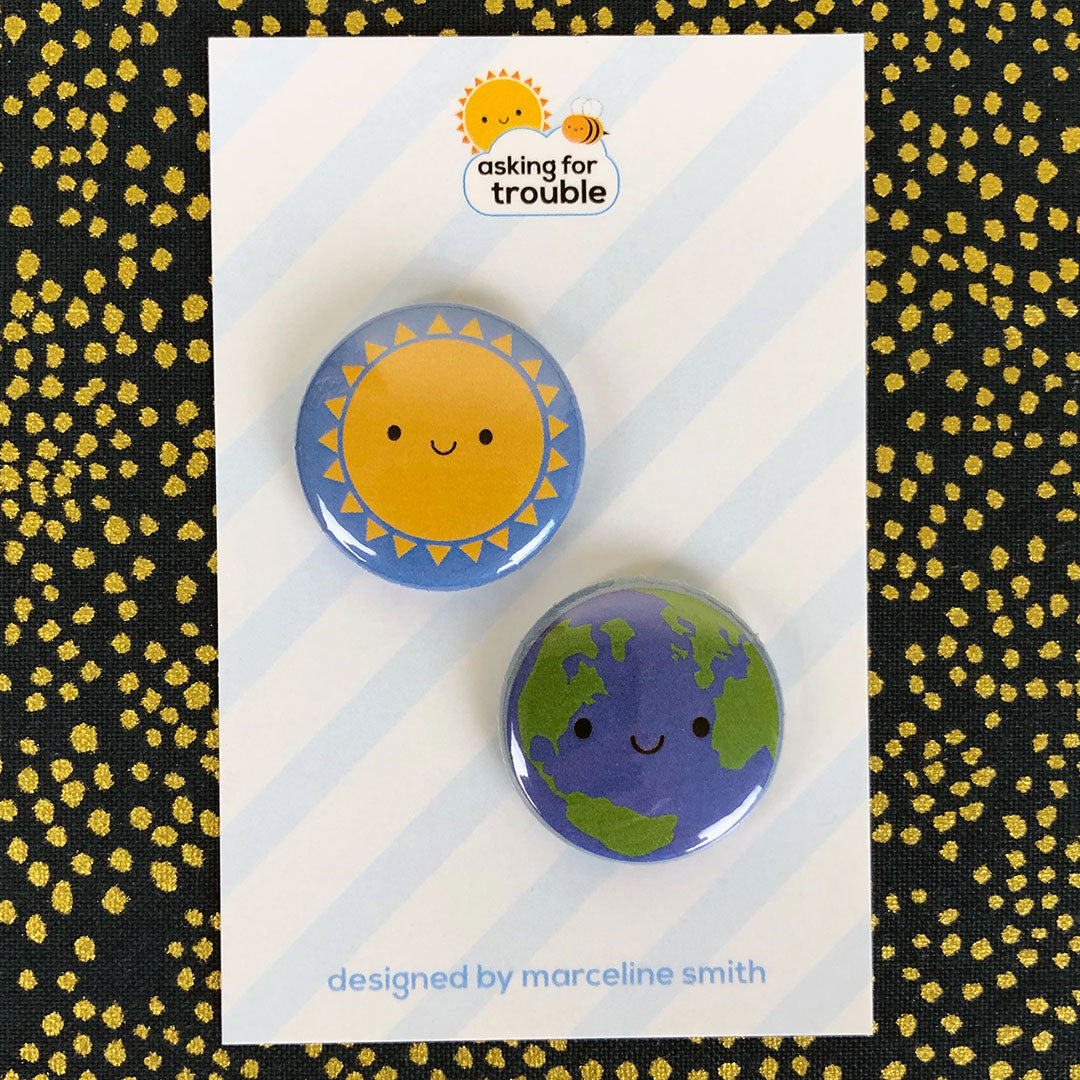 Sun & Earth badges packaged together on a striped backing card