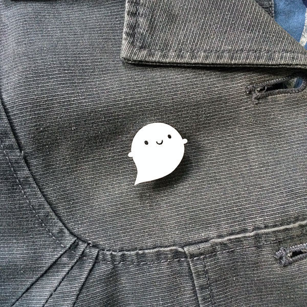 A Little Ghost brooch pinned to a grey jacket