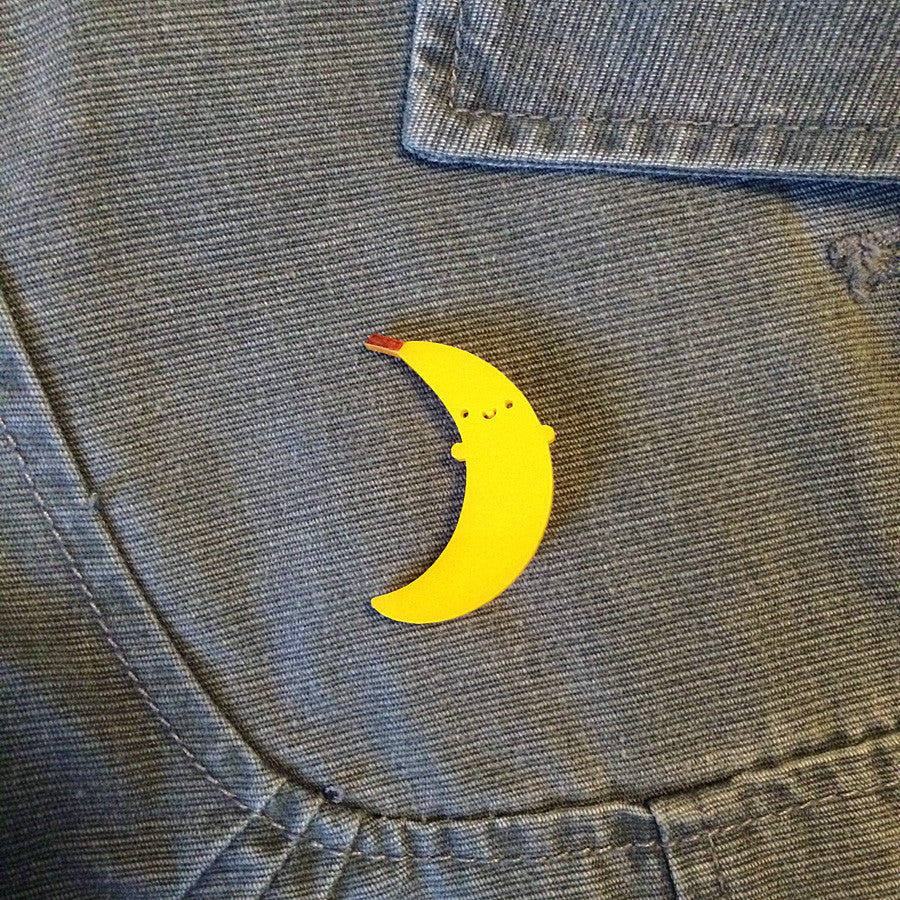 A happy banana acrylic brooch pinned to grey jacket
