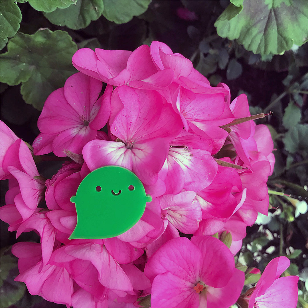 The green Rainbow Ghost brooch sitting on a pink flower