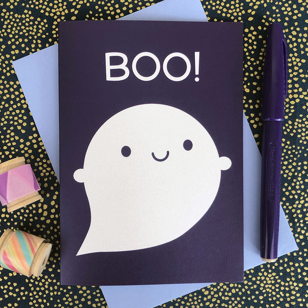 An illustrated card with a happy ghost and the word BOO! on a purple background