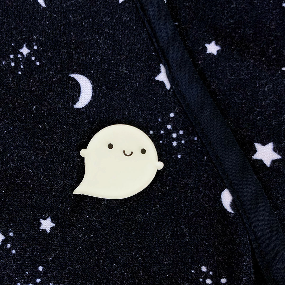 A glow in the dark ghost brooch pinned to star-patterned fabric
