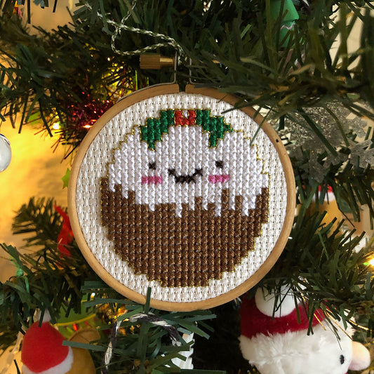 The finished Christmas Pudding cross stitch, framed in a small hoop and hung on a tree