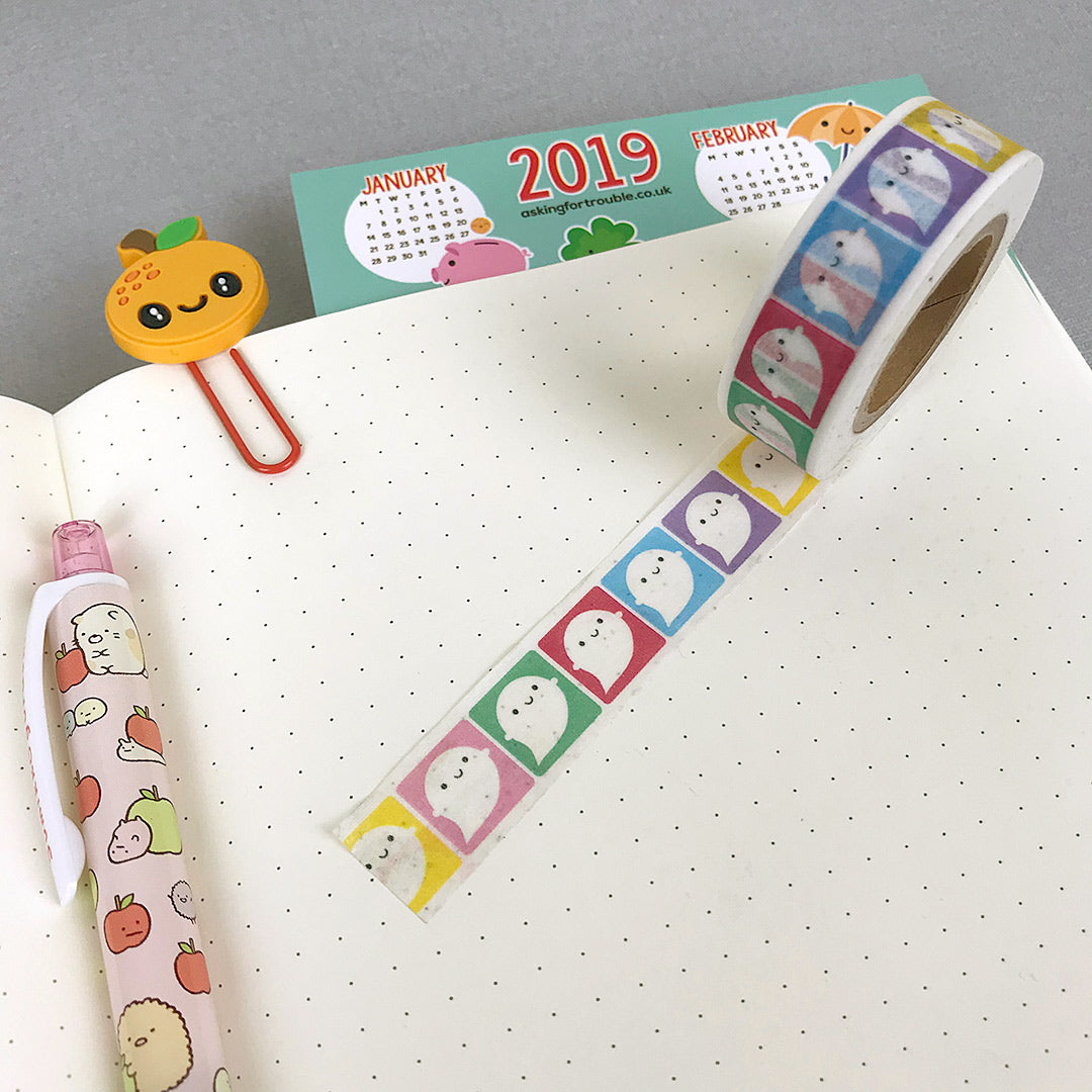 A roll of Rainbow Ghosts washi tape partially unrolled to show the design on a journal page