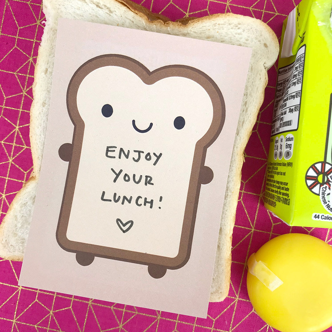 A cute Bread Slice memo sheet with 'enjoy your lunch' written inside, placed on a packed lunch