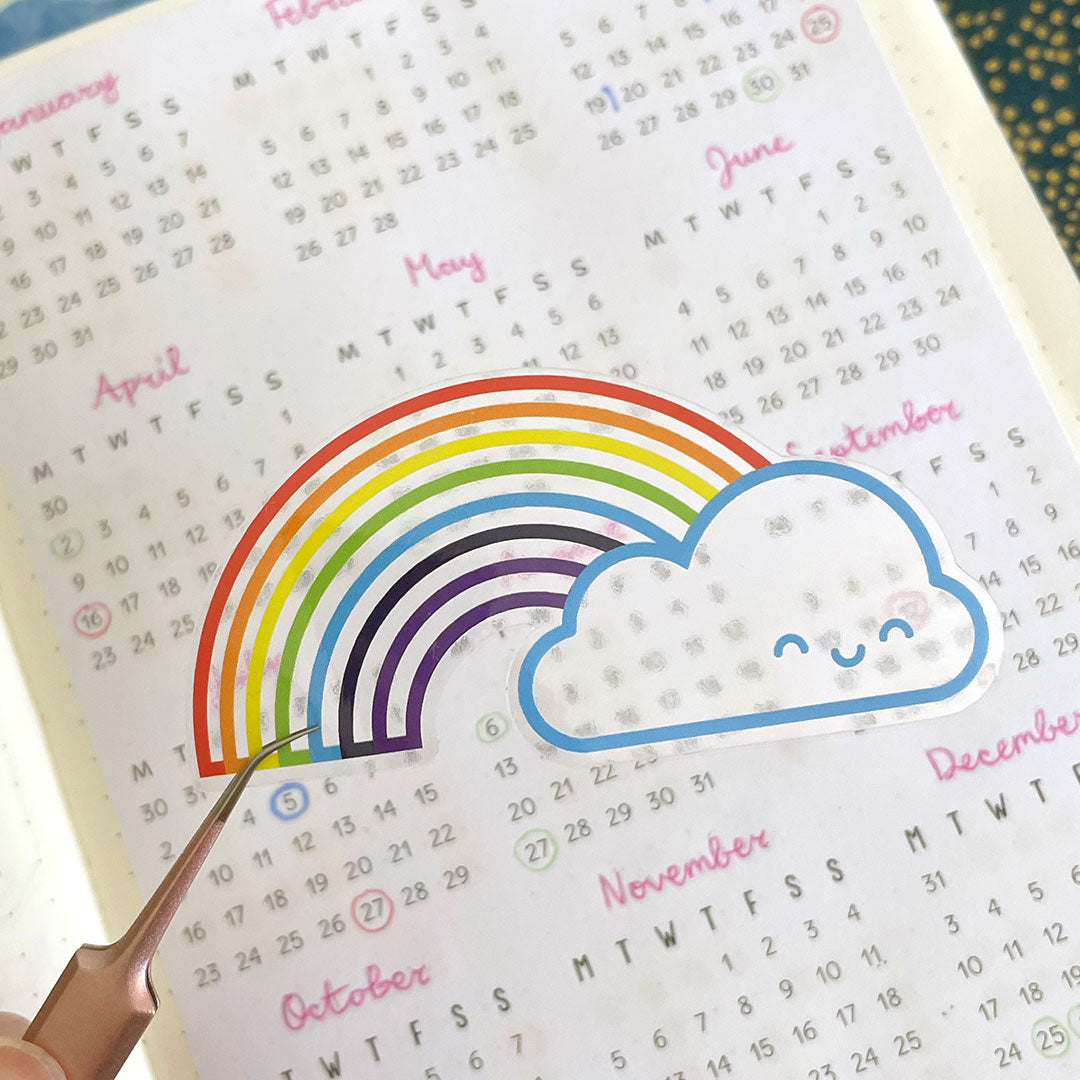 A clear transparent Rainbow sticker held over a printed page