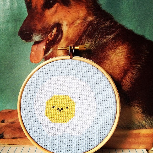 A finished Fried Egg cross stitch framed in a hoop