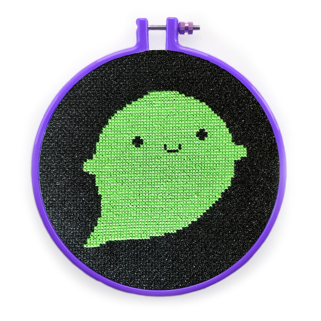 The aida used for a neon green ghost cross stitch design framed in a hoop
