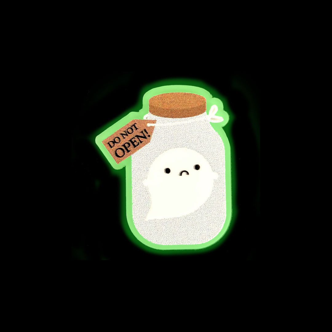 The limited edition glow in the dark Trapped Ghost brooch featuring a sad ghost inside a corked jar with a 'do not open' label